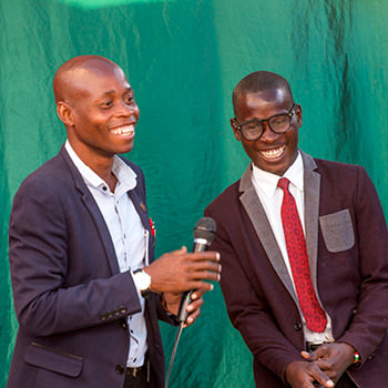 Two African men in a stage holding a microphone